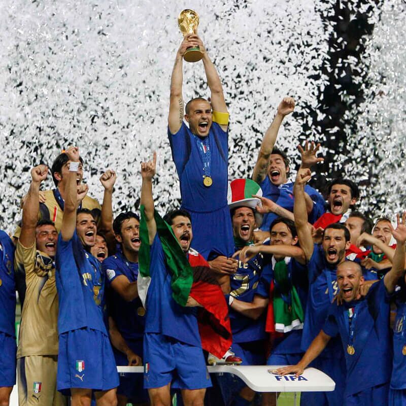Football team celebrating with World Cup trophy under falling white confetti