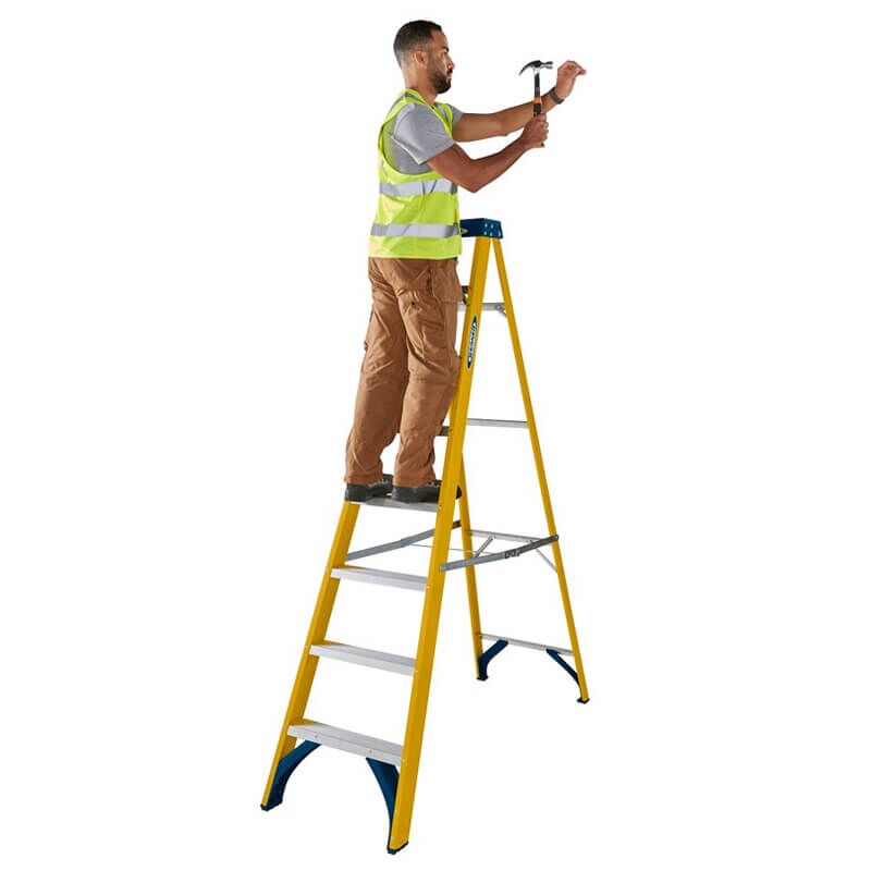 Man using Werner Fibreglass Stepladder 8 Treads 2.2m to hammer overhead