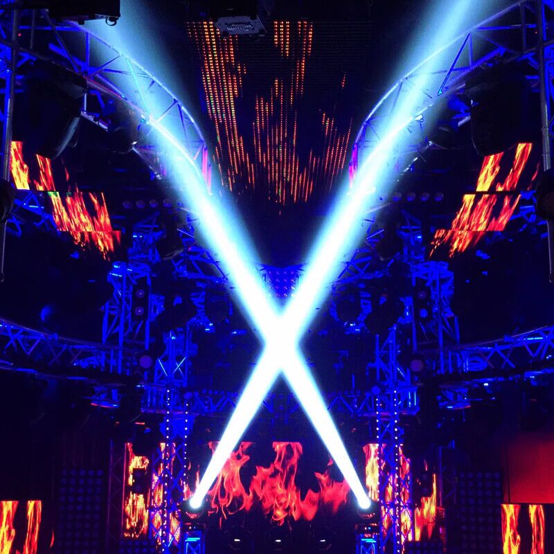 Vizi Beam 5RX fixtures creating intersecting white beams of light on a stage setup with LED screens and trusses